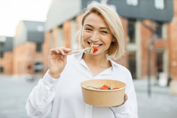 仕事中に休憩しながら健康的なサラダを食べる笑顔のビジネス女性の肖像画 親切なPositiv女性食べる彼女のサラダながら 街の通りにある — ストック写真