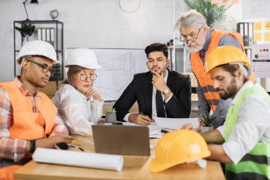 Nitelikli mimarlar, mühendisler ve tasarımcılar ofiste önemli bir oturum sırasında proje planını ayrıntılı olarak tartışıyorlar. İnşaat ekibinin iş toplantısı. Sorumluluk kavramı.