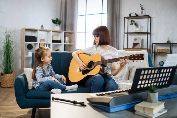 Gyönyörű Fiatal Bájos Kislánya Mosolyognak Miközben Otthon Akusztikus Gitároznak Anya — Stock Fotó