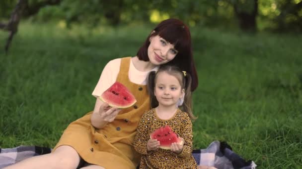 夏天的时候两个快乐的家庭 妈妈和她的小女孩在城市公园野餐 有趣的高加索妈妈和女儿在野餐时吃西瓜 — 图库视频影像