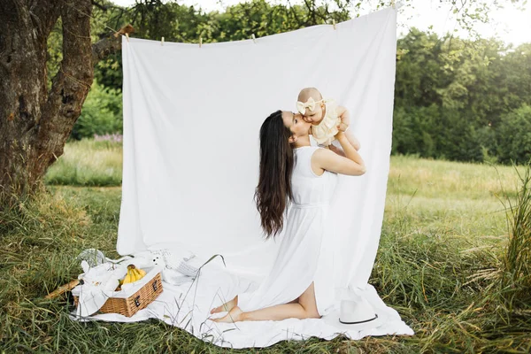 Uma Jovem Mãe Solteira Beijando Bochecha Sua Filhinha Sentada Grama — Fotografia de Stock