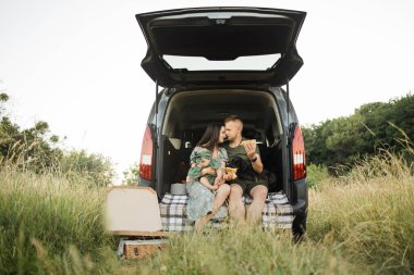 Gülümseyen genç ebeveynlerin portresi küçük kızlarını ve köpeklerini lezzetli pizzayla utandırıyor. Üç kişilik mutlu bir aile hafta sonu partisi veriyor..