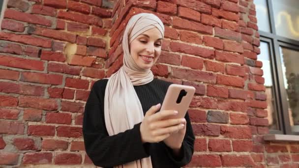 Fröhliche Junge Islamische Geschäftsfrau Die Der Nähe Einer Roten Backsteinmauer — Stockvideo