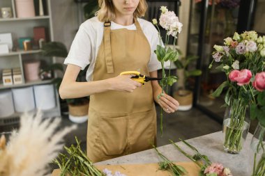 Çiçekçi eski yaprakları keserken dükkânda güzel bir bahar çiçeği buketi yaparken kesilen manzarayı kapat. Modern bayan çiçekçi dükkanda bir iş günü geçiriyor..