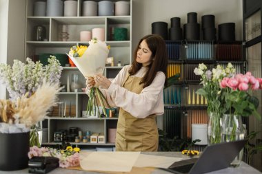Çiçekçilik yapan çekici bir kız. Çiçekleri buketlere yerleştirmek ve birbirlerine tavsiyelerde bulunmak. Çiçekçide çiçek satıyorum..