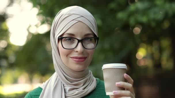 Aantrekkelijke Glimlachende Moslimvrouw Hijab Met Een Kopje Afhaalkoffie Groene Achtergrond — Stockvideo