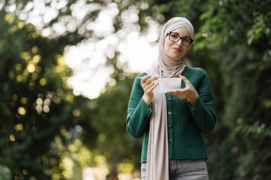 Portrait of happy muslim smiling woman freelancer, manager, business lady, eating fresh vegetable salad during lunch break outdoor in the city park.