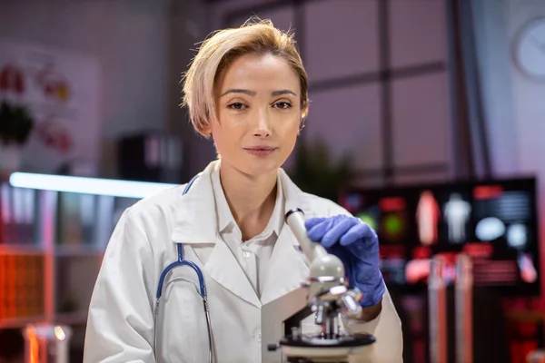 Modern medical research laboratory: portrait of scientist working, using microscope, analyzing samples. Advanced scientific pharmaceutical lab for medicine, biotechnology development.