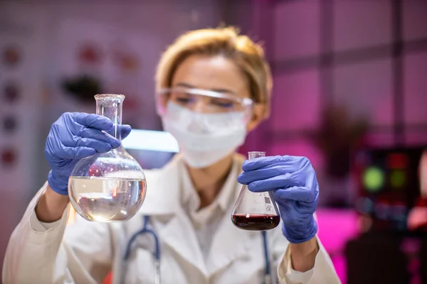 Female scientist testing experiment in a science lab where she holding scientific test tube full of chemical substance. The researcher is analyzing medicine related innovation. Microbiology concept.