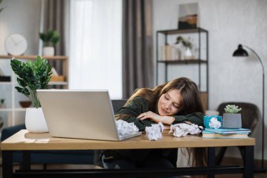 Indoor picture of smiling and tired woman sleeping on the table. Young adult business fatigue woman sleeping on table at office. Business woman tired from working overtime.