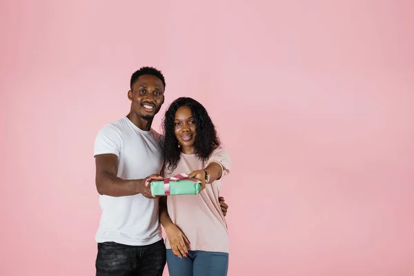 Cheerful Beautiful African American Couple Showing Gift Pink Studio Background — Zdjęcie stockowe