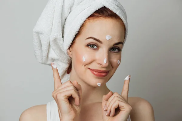 Beautiful Young Woman Applying Face Cream Looking Camera Grey Studio — Stockfoto