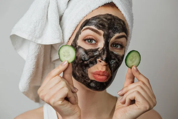 Smiling Young Woman Black Clay Mask Face Holding Fresh Cucumber — Stok Foto