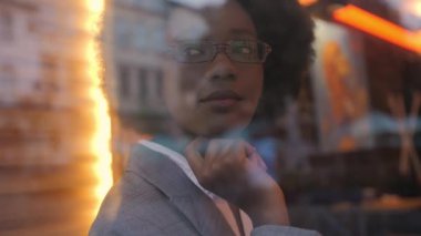 Confident business woman on stylish suit looking at panoramic window while sitting at cafe table during break. Working process indoors.