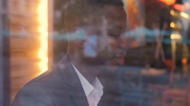 Perspective african man in stylish suit drinking coffee and working at cafe. Confident young businessman resting during a break.