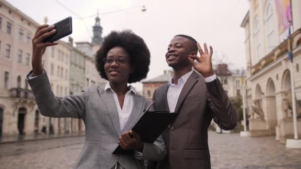 成功したアフロアメリカのビジネスの人々は 街の通りに一緒に立って スマートフォンで自撮り 若いです男と女でフォーマル服笑顔とジェスチャーオンカメラ — ストック動画