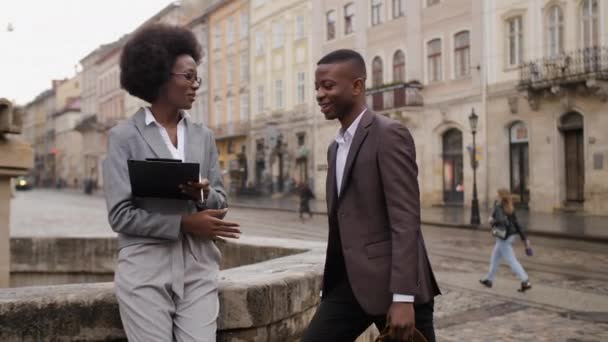 美丽的非洲女人和英俊的男人在城市街道上相遇 两个穿着正式服装的商业伙伴讨论户外工作时间 — 图库视频影像