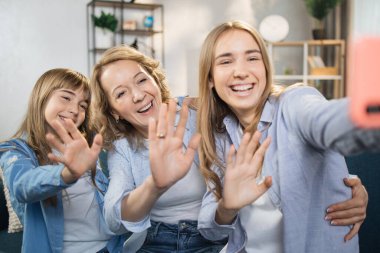 Attractive two people two young lady girls sisters and their mother using mobile phone taking photo