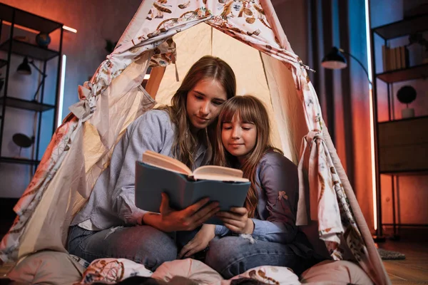 Caucasian Pretty Blond Sisters Sitting Wigwam Reading Book Evening Time — Stockfoto