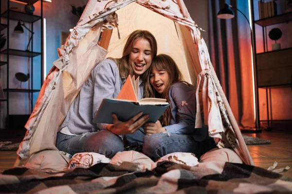 Caucasian Pretty Blond Sisters Sitting Wigwam Reading Book Evening Time — Stockfoto