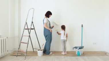 Genç anne ve küçük tatlı kızının duvar boyarken eğlendikleri uzun bir portre..