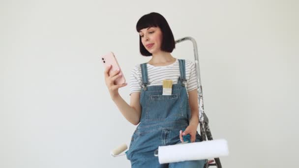 Retrato Menina Caucasiana Segurando Rolo Tinta Usando Smartphone Sentado Uma — Vídeo de Stock