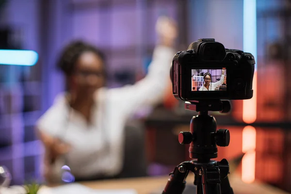 View of video camera screen with attractive confident african american skilled business woman explaining online economic charts on glass board to her colleagues.