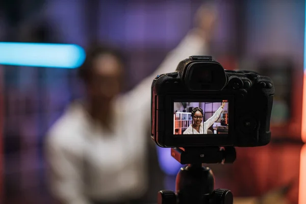 View of video camera screen with attractive confident african american skilled business woman explaining online economic charts on glass board to her colleagues.