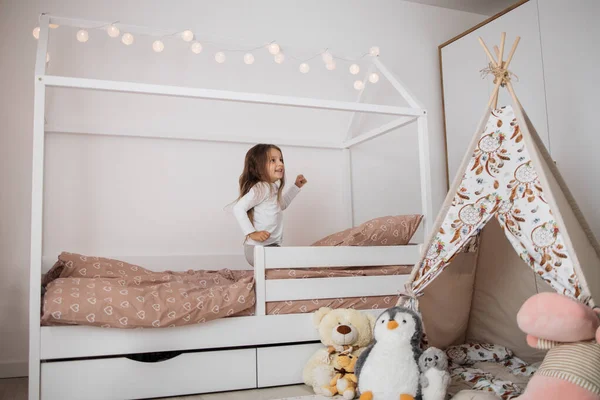 Evdeki Beyaz Skandinav Ahşap Yatağının Üzerine Atlayan Şirin Mutlu Beyaz — Stok fotoğraf