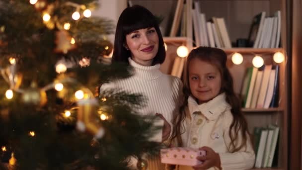 可爱的年轻白种人妈妈和可爱的小女儿在冷杉树上抱着圣诞礼物 微笑的母亲和女孩在家里庆祝新年 — 图库视频影像
