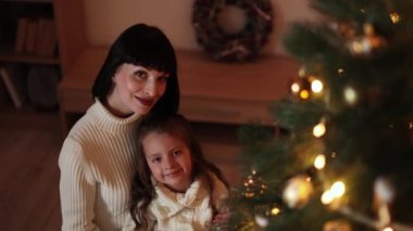 Anne ve kızı evde Noel ağacı süslüyorlar. Bir çocuk odasının şık bir iç mekanı. İskandinav eko-tarzı dekor. Yeni yıl kutlaması. Noel arifesi. Ortak zaman yönlendirmesini destekleyin. Aşk