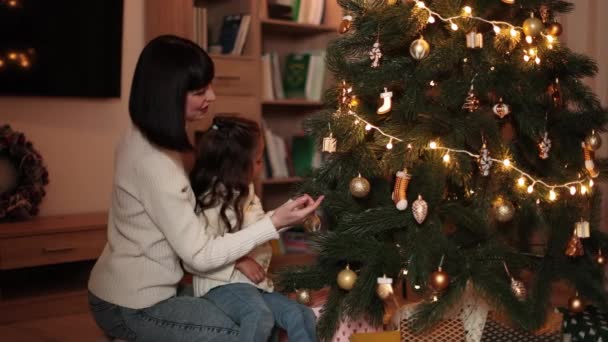 미취학 어머니와 크리스마스 트리를 장식하고 가지에 장난감을 집에서 축하를 준비하는 — 비디오