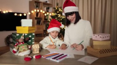 Mutlu bir aile, genç güzel bir anne ve kırmızı şapkalı şirin bir kız çocuğu Noel arifesinde Noel Baba 'ya mektup yazıyorlar..