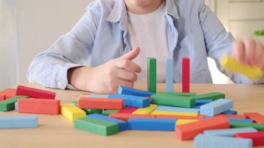 Çocuk renkli ahşap tuğlalarla kule inşa ederek oynuyor. Motor beceriler gelişiyor. Evde oyun oyna