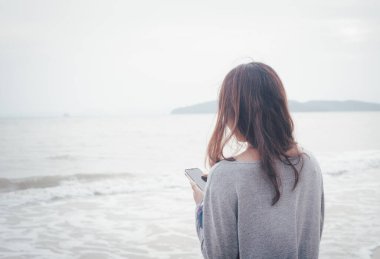 Yalnız bir kadın, deniz arka planında fırtınalı bir deniz yüzeyinde tek başına yürüyor.