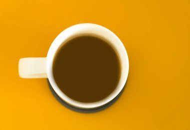 Sarı arka planda bir fincan koyu kahvenin üst görüntüsü