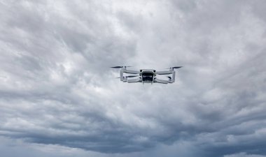 A high-tech drone in the sky Professional filming drone flies in the air at a low altitude against a sky and sea sandy beach. The drone makes photos. Modern new technology.