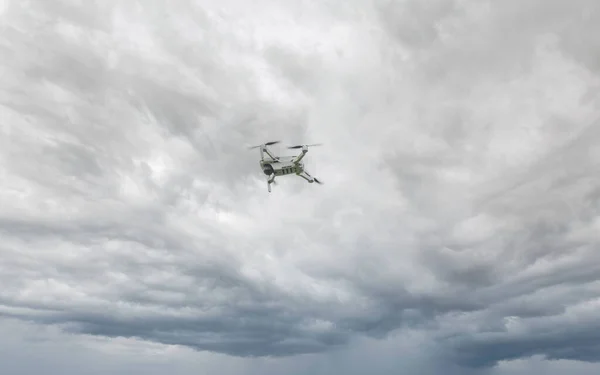 A high-tech drone in the sky Professional filming drone flies in the air at a low altitude against a sky and sea sandy beach. The drone makes photos. Modern new technology.