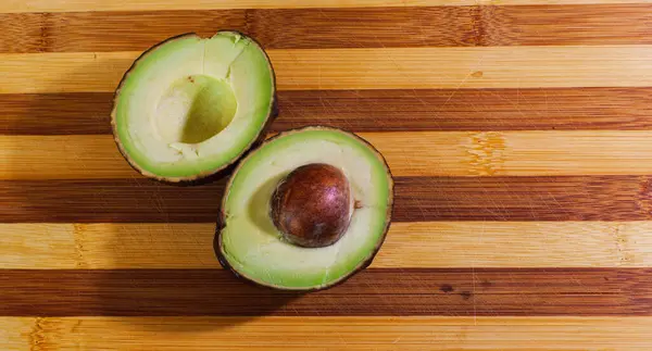 Cut Avocado Lies Yellow Board Ripe Avocado Stone Healthly Food — Stock Photo, Image