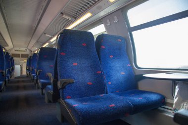 Koltukları olan boş bir vagon. Arabanın içine giden bir geçidi olan boş tren koltukları. Koltukların yanında bir pencere ve bir masa var. Yalnız seyahat et. Arabadaki koltuklar mavi ve hiç insan yok..