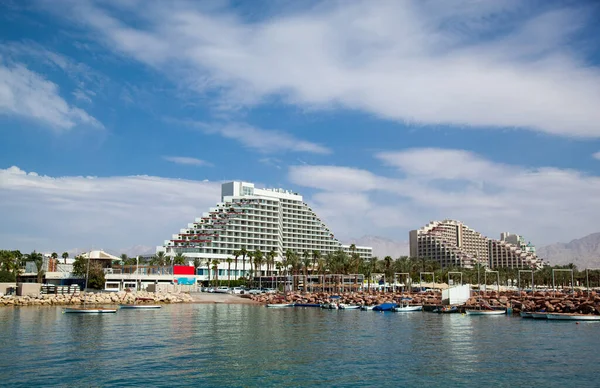 View of the hotels in Eilat in Israel. Resort town on the Red Sea. Hotel complex for tourists and recreation. Resort infrastructure. Beautiful hotel on the background of the sea and blue sky with clouds