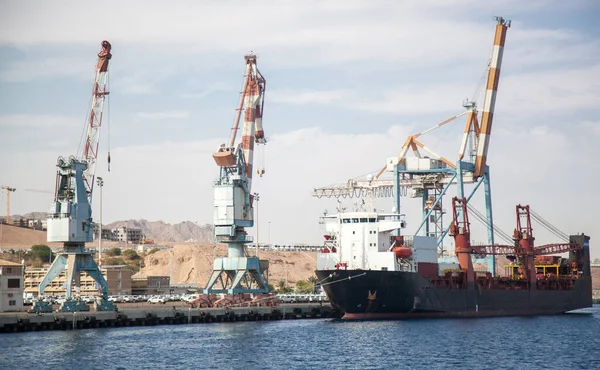 Large loading cranes in the international port of Israel. A ship is moored near the cranes, waiting for the goods to be loaded on board. International logistics and trade. Water freight transport, infrastructure