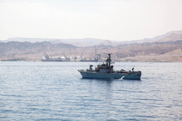 A military boat passes through the Red Sea in Eilat. Against the background of the boat, a pear port and hilly mountains are visible. Boat with echolocation systems on board. duty warship