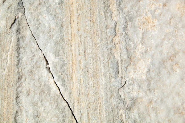 The texture of a white stone with a crack. Stone resembling marble. Build material for interiors and construction of houses. The texture of the stone with vertical stripes of white and milky color