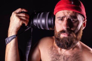The photographer stares pleadingly into the frame. The camera lens is aimed at the temple of the model. Information load on a person. Man on a black background