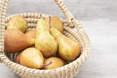 Hasır sepetin içindeki olgun armutlar ahşap masa, üst manzara, lezzetli meyve suyu hasadı.,