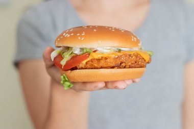 Elde vejetaryen burger. Bitki temelli diyet konsepti. Açık hava kafede oturan bir kadının ellerinde hamburger.