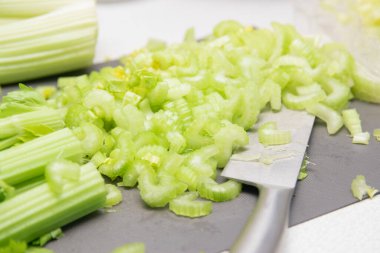 Taze dilimlenmiş kereviz. Kereviz saplarını ve yaprakları ahşap masada kes. Yapraklı taze kereviz sapı. Kerevizi kurutmak için hazırlıyorum. Meyve ve sebze kurutma makinesi
