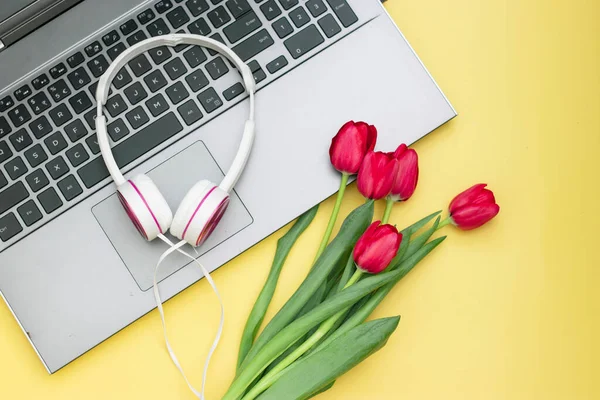 Bouquet of tulips with laptop, on yellow background. Online flower shop. Top view. Flat lay.