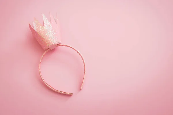 Pink princess crown headband for girls on pink background. Festive girlie feminine birthday party or performance. Flat lay minimalistic with copy space.